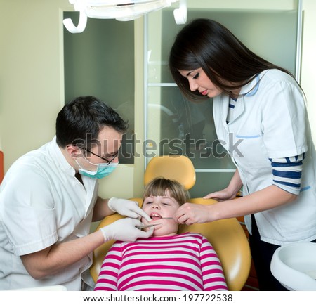 little girl to the dentist in the dental chair sits next to a doctor to do the dentist to see if his teeth were okay/ little girl at the dentist