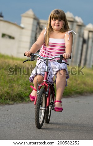 A little girl rides a bicycle on the road/ bicycle