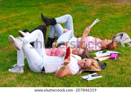 young college or high school student a break from learning on the grass in the park with his feet cocked in the air/happy young highschool students