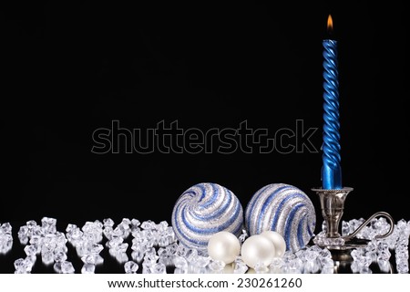 silver candlestick with one blue candle and glass balls stands next to a multitude of crystal stones on the mirror/silver candlestick with one blue candle