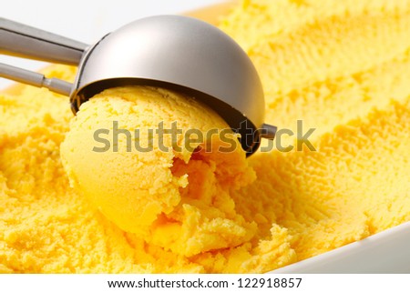 Yellow fruit flavored ice cream and scoop