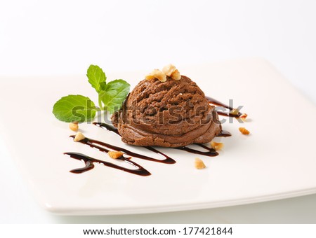 scoop of chocolate ice cream sprinkled with grated nuts, decorated with syrup wave