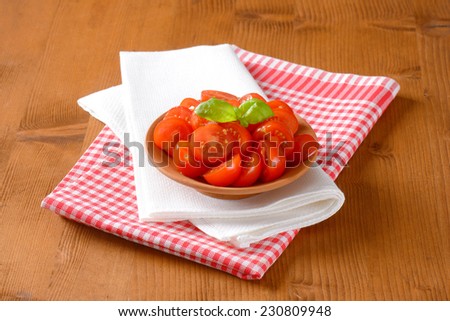 halved cherry  tomatoes with basil, served in the bowl with two kinds of fabric linen