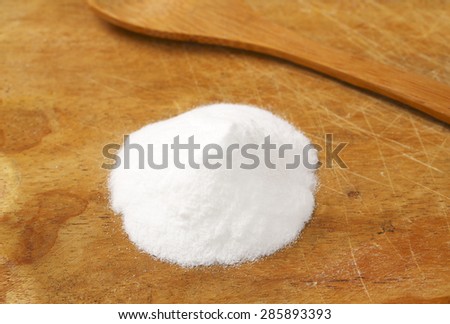 handful of cooking soda and spoon on wooden cutting board