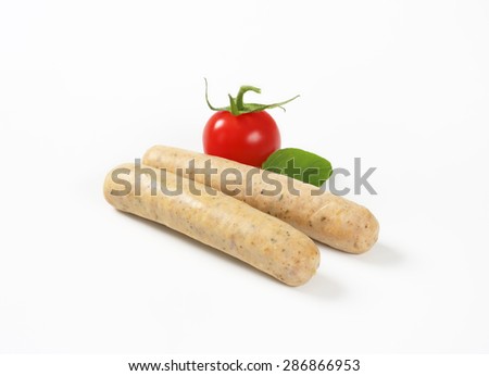 pair of white sausages, fresh basil and cherry tomato on white background