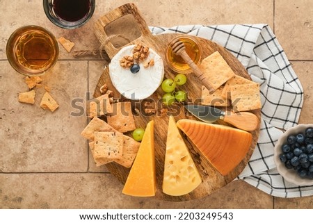 Assortment of cheese, honey, cracker, blueberries, grapes with red and white wine in glasses antipasto server on white marble board on grey background. Cheese plate. Flat lay, copy space. Foto d'archivio © 