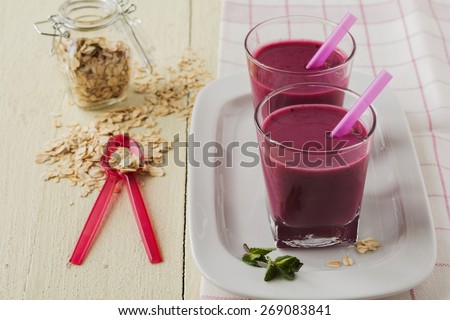 Smoothie made with frozen red berries,milk, and oatmeal in a glasses in wooden background.Selective focus.