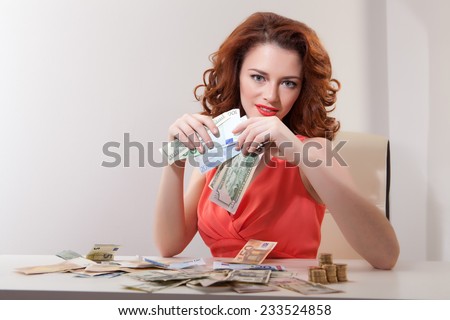 young girl at  table with greedy counts money lying on  table and looking at  camera