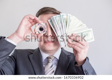 Businessman in suit holds in hands,looks to drop of black oil of Brent brand.Crystal cube.Pack of hundred dollars bills.Crisis in financial market,falling,rising prices,quotes,change in exchange rate