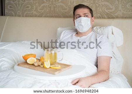 Cup with antipyretic drugs for colds,flu.Sick man in bed. Tea with citrus vitamin C,ginger root,lemon,orange.Wooden tray. Home self-treatment.Medical quarantine antiviral covid-19 coronavirus therapy. Stok fotoğraf © 