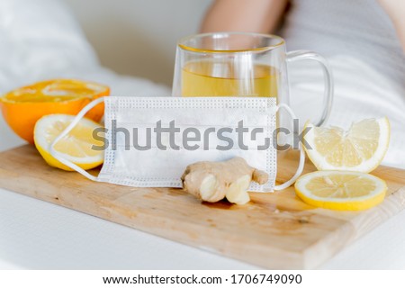 Face children's mask.Cup of tea with citrus vitamin C,ginger root,lemon,orange.Antipyretic drugs. Colds,flu.Wooden tray. Home self-treatment.Medical quarantine antiviral therapy.Covid-19, coronavirus. Stok fotoğraf © 