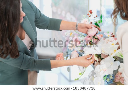 Woman florist on wedding makes flower composition for bride and groom from roses, tulips, peonies, orchids on table. Decorators working at event: birthday, anniversary, party. Hand with floral tattoo. Stock fotó © 