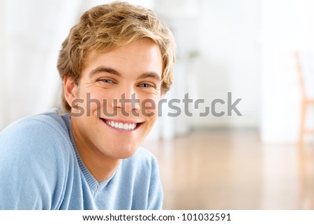 Happy young man relaxing at home looking at camera smiling