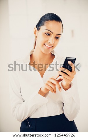 Indian business woman sending text message mobile phone happy