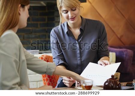 Two businesswoman reading documents working on business meeting on cafe