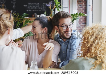 Woman showing engagement ring to friends in cafe celebrating