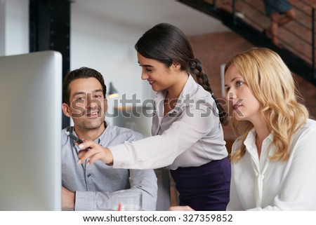 Businessmen and businesswomen working over computer in busy office