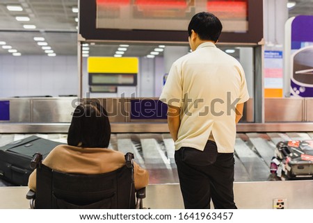 Caretaker with senior woman in wheelchair wiat for luggage on conveyor belt in the airport. Zdjęcia stock © 