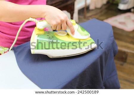 Woman ironing a blue shirt with a steam iron in blur background shirt with a steam iron in blur background