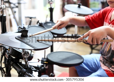 Unidentified Asian boy play electronic drum in music room