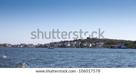 Scenic view over a part of the swedish west coast. A sail boat is sailing and you can see summer homes in the background.