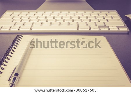 Notebook with pencil in front of computer on desk vintage color