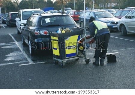 cleaner with his cart washing cars in car park