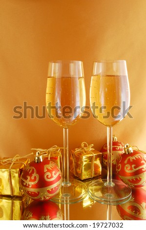 Two glasses with champagne and gifts on gold background