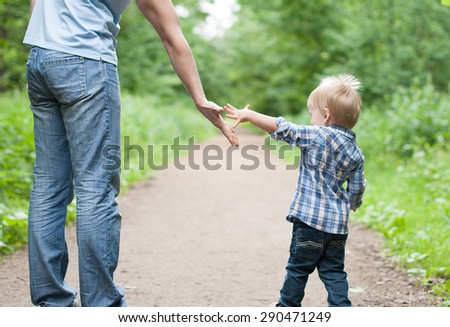 Father and son go in a park. Father gives hand the son