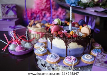 Beautiful purple cake with macaron and biscuits on the table