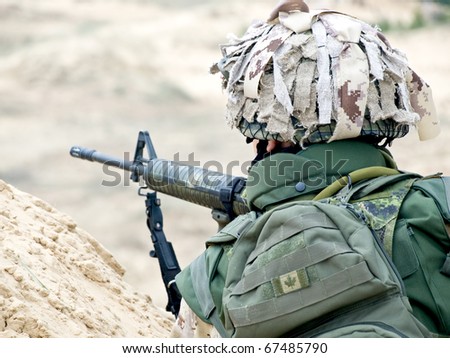 soldier in desert uniform aiming his rifle