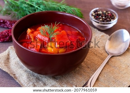 lecho of tomatoes and red peppers with ingredients on the table. lecso national dish of Hungarian cuisine with spoon and greens in the white bowl. Hungarian food. copy space. Stock fotó © 