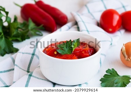 close-up lecso national dish of Hungarian cuisine with pepper and tomato, greens on the white plate. lecho of tomatoes and sweet paprika with ingredients on the table. Hungarian food. copy space. Stock fotó © 
