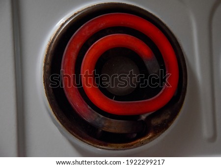 Electric stove, hot spiral at the stove. Bright red spiral curls side view. Red hot, glowing element. Electric stove with a spiral. Heating element on an electric stove. view from above