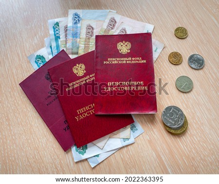 Russian pension certificates are stacked on top of each other. Paper and metal rubles are under documents and next to them.