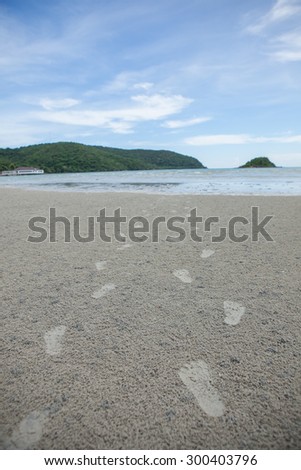 Footprints of two people on the sand . Represents a walk together . On the backdrop of the sand and the sea.