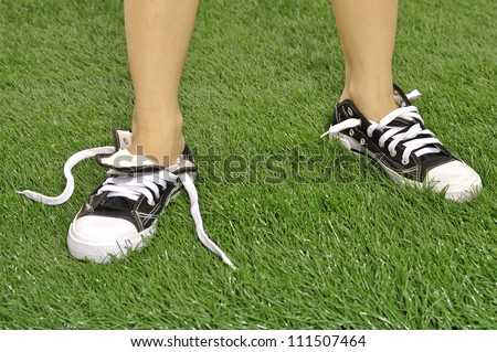 Kid with untied shoes on the green grass