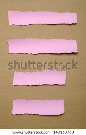 Torn pink paper scraps on brown cardboard background. You can put your design on the paper