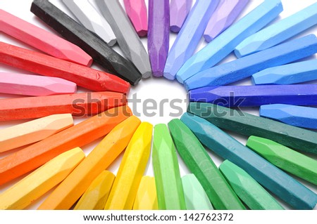 Row of colorful crayon making circle shape over white background