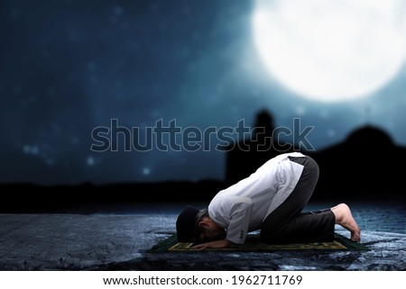 Asian Muslim man in praying position (salat) on prayer rug with the night scene background Imagine de stoc © 
