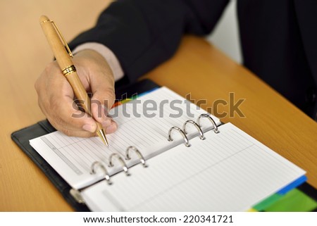 Business Man writing on agenda on the desk