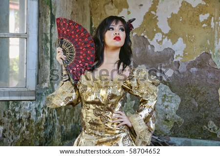 Chinese woman wearing victorian costume holding a fan, shoot at grunge building