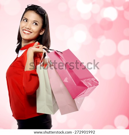 Portrait of young happy woman with shopping bags over blurred background