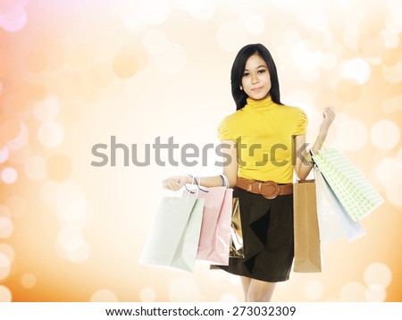 Full body asian woman hold shopping bags over blur yellow background