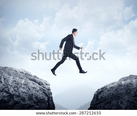 Business man jumping across hill. Business challenge conceptual