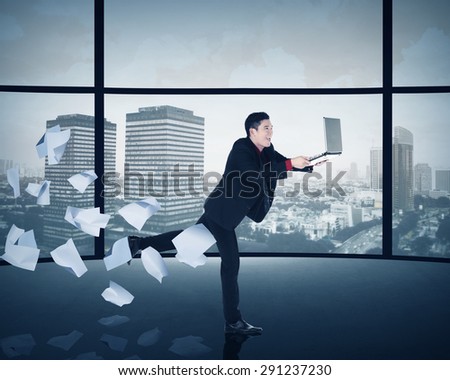 Asian business man running with laptop inside office building