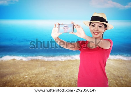 Asian tourist take selfie on the beach in summer