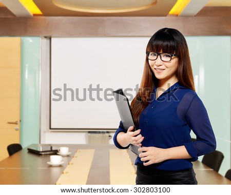 Asian business woman holding folder, smiling with office background