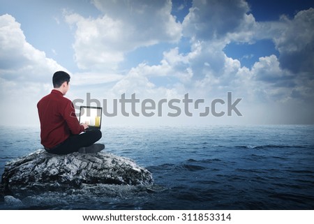 Business man sitting on the top of the rock in the middle of the sea