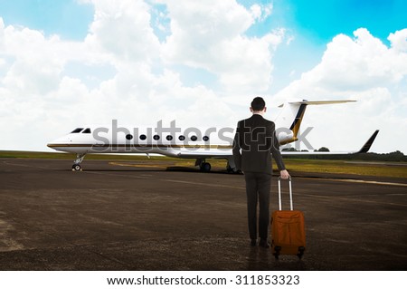 Business man carrying suitcase to the airplane in the airport